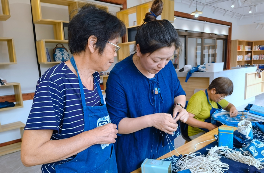 老人正在對藍印花布作品進行縫紉。段凌云攝