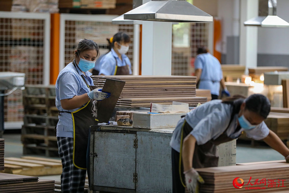 近日，在湖州市南潯區一地板企業，工作人員在對地板進行加工。人民網 章勇濤攝