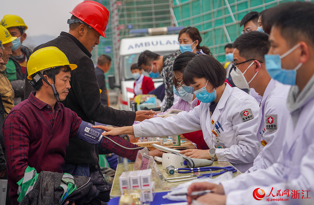 3月1日，在杭州市拱墅區(qū)石橋街道，一名醫(yī)護(hù)志愿者在為工人測(cè)量血壓。人民網(wǎng) 章勇濤攝