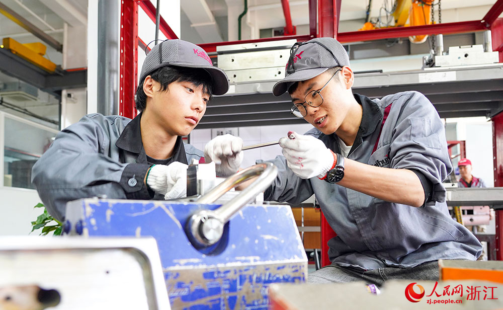 在臺州科技職業學院凱華模具產業學院，高級鉗工余葉敏（右）在指導學生對模具滑塊進行絲攻操作。人民網 章勇濤攝