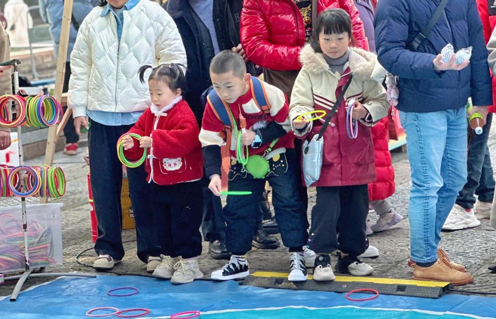 新春集市上，小朋友們正在套圈。費祎攝