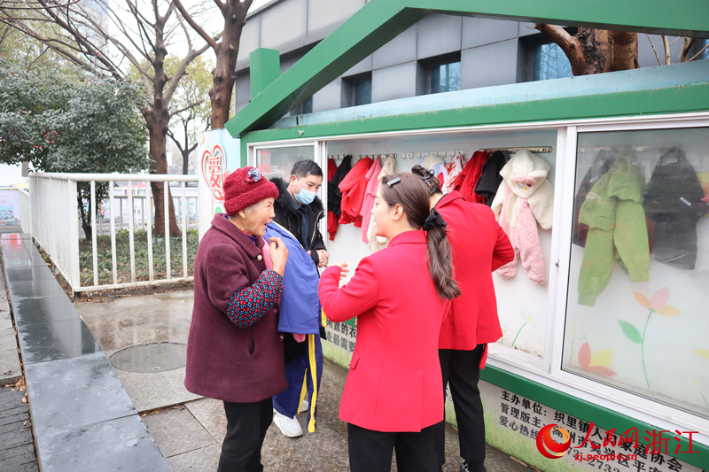 周邊居民聚集在志愿者身邊，滿心歡喜地領取童裝。人民網 孫鵬攝