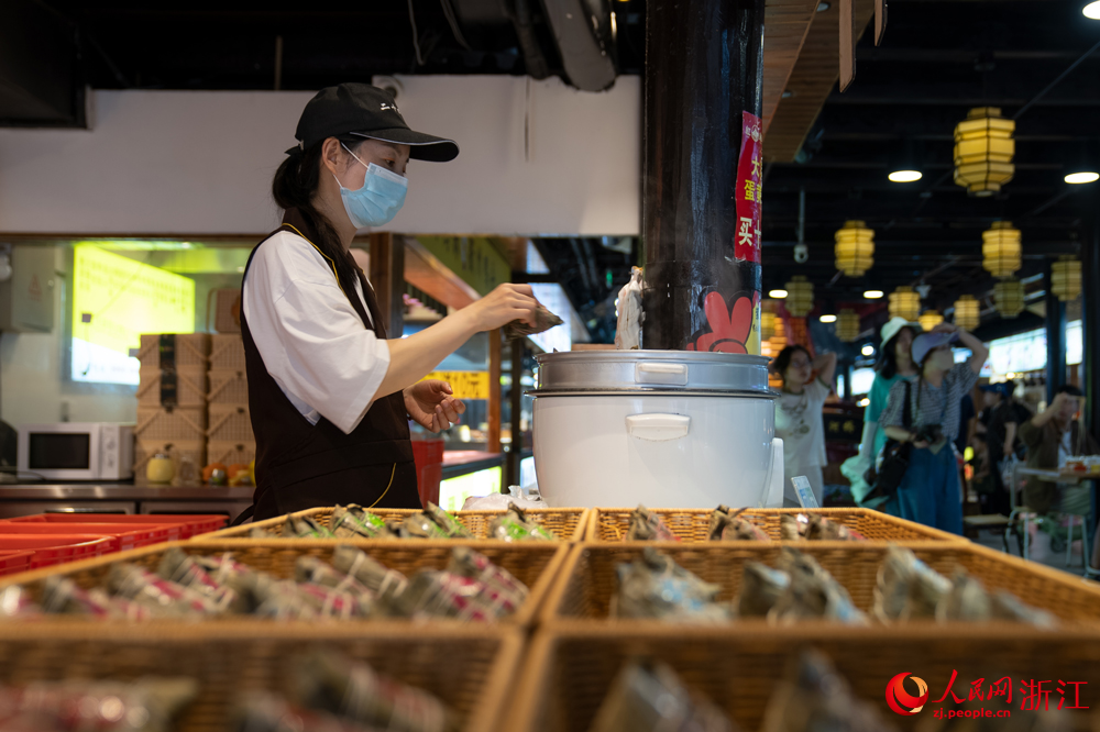 5月26日，端午將至，浙江省嘉興市月河街的一處店鋪內(nèi)，店員將剛包好的粽子放入鍋中。人民網(wǎng)記者 葛泰佚攝