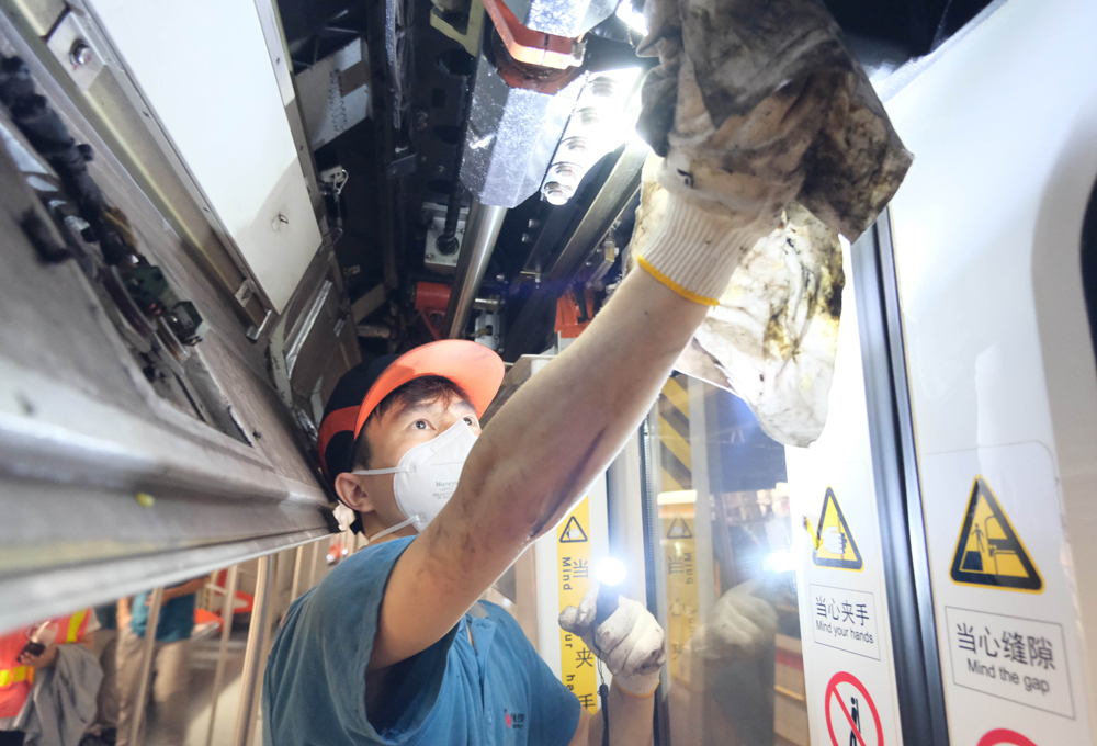 地鐵車輛檢修員正在檢查車輛部件磨損情況。程欣攝